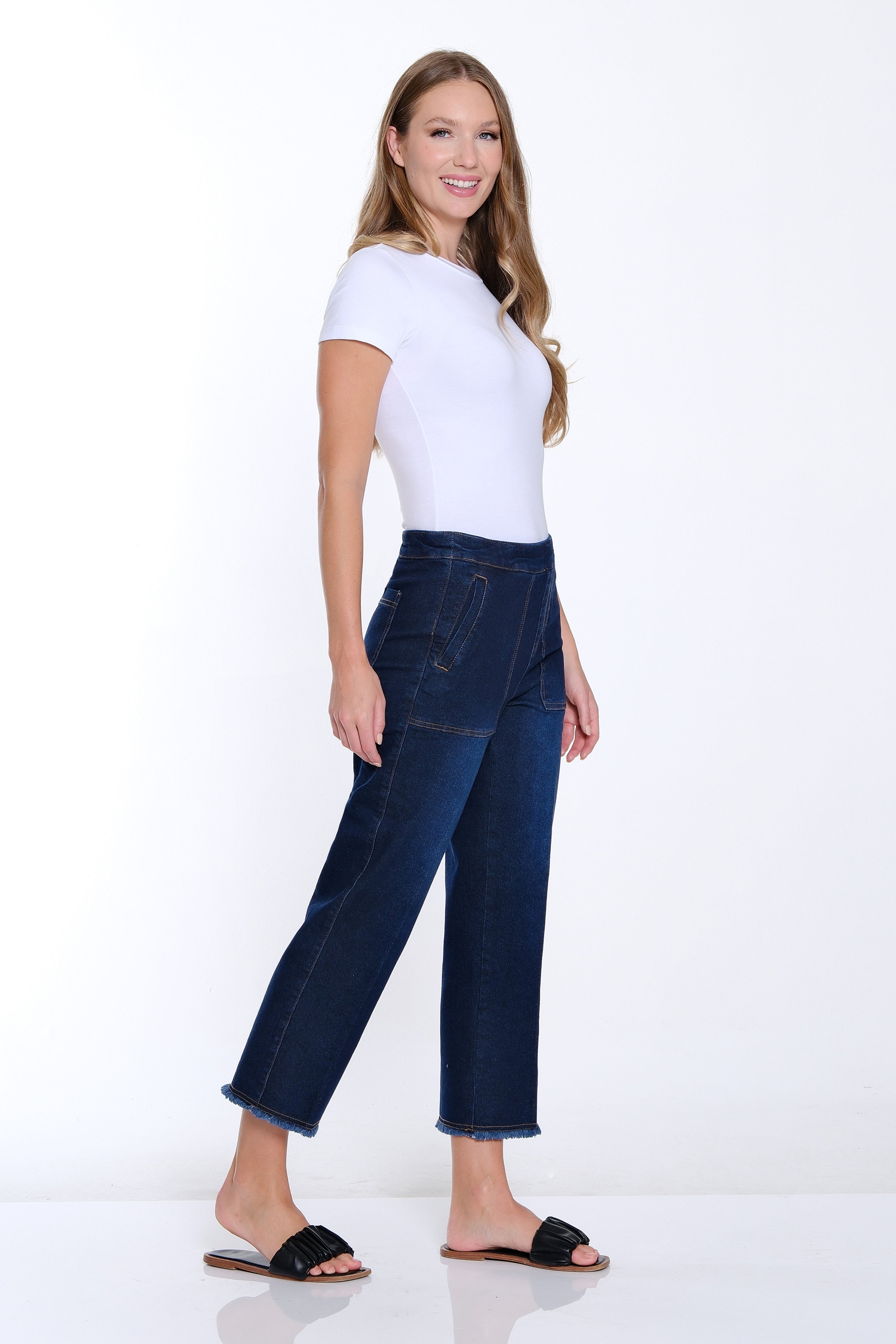Woman wearing a white top and blue jeans on a white background