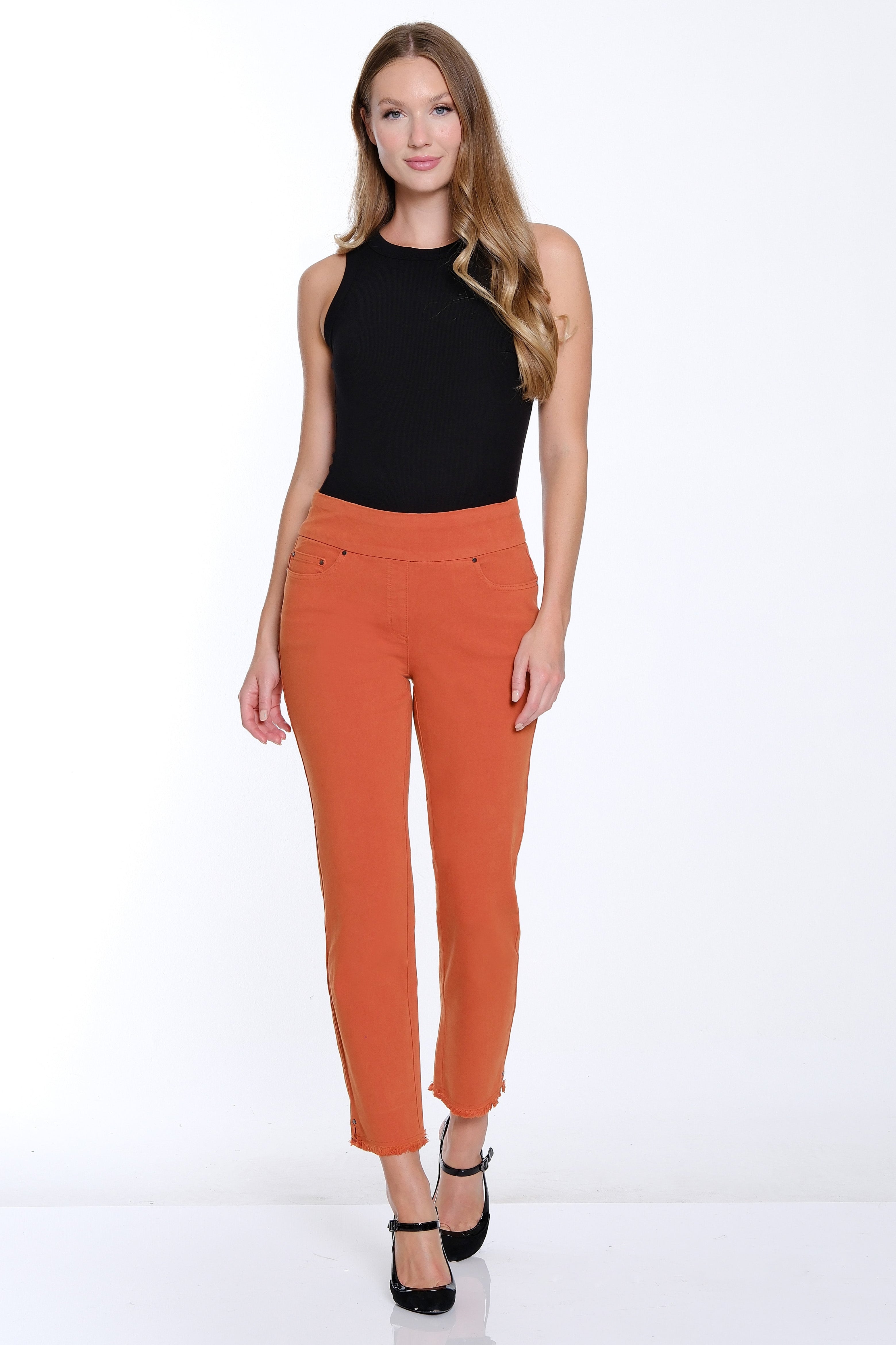 Woman wearing a black top and orange pants on a white background