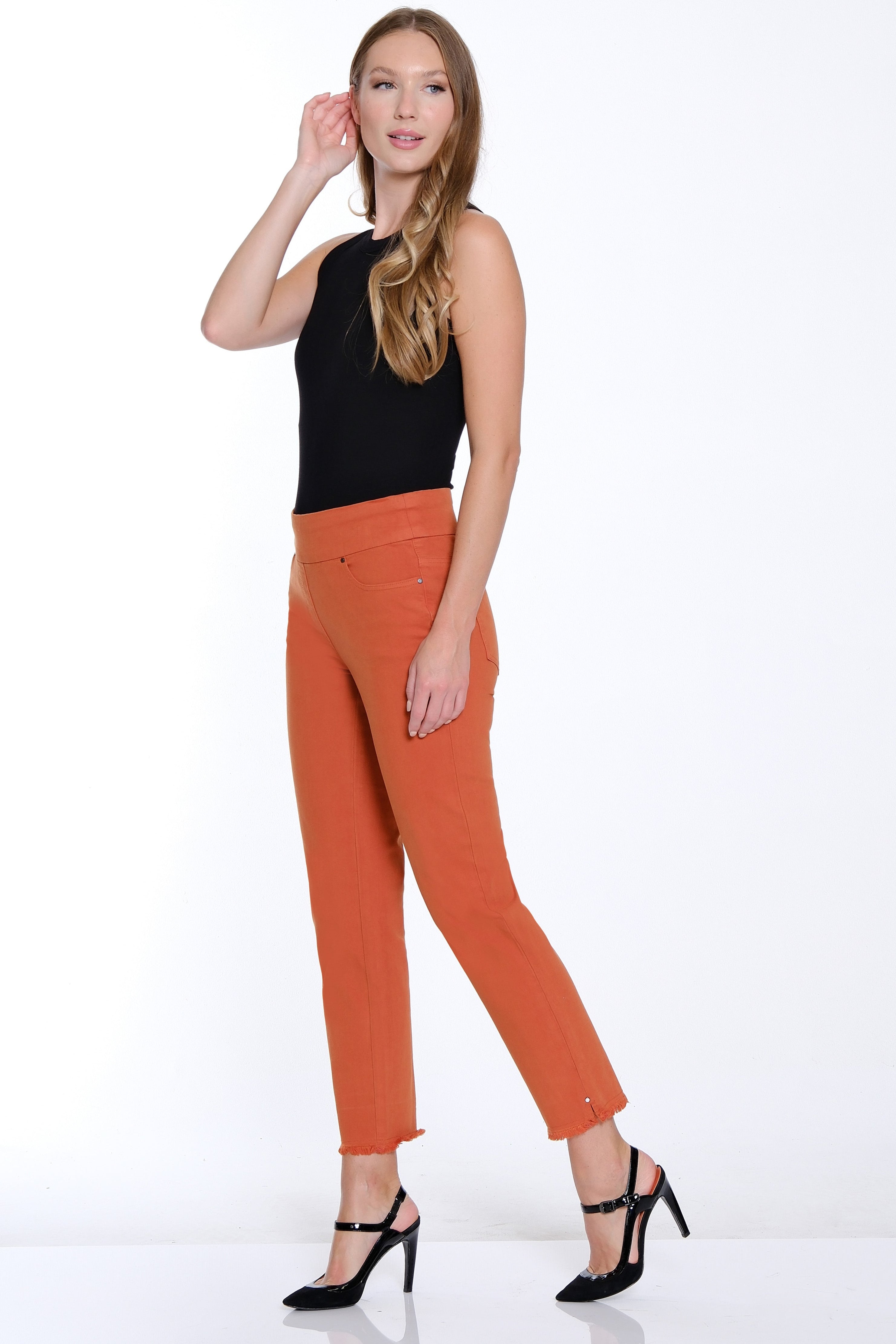 Woman wearing a black top and orange pants on a white background